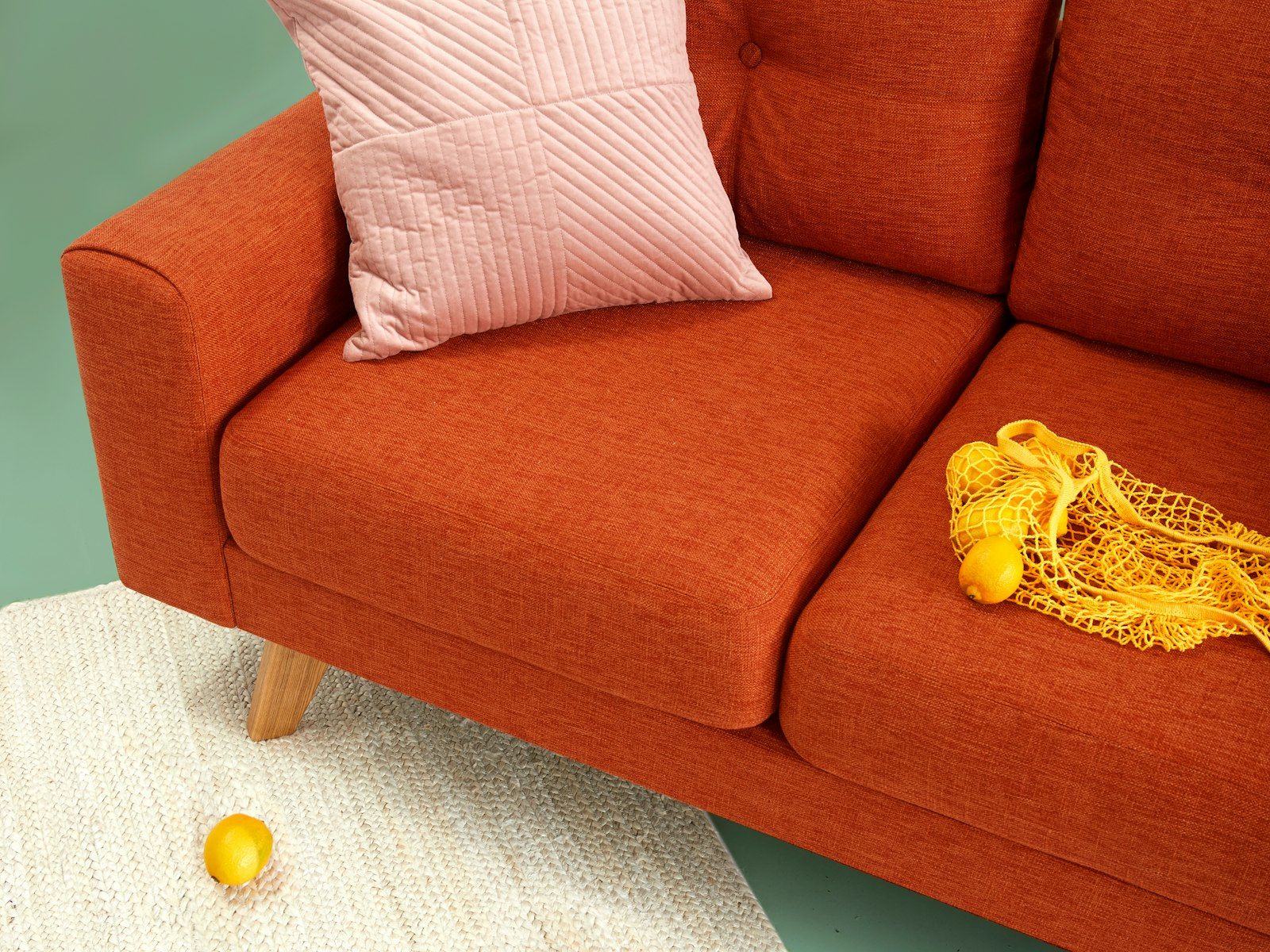 A bright orange sofa with a pink cushion in a calm room.